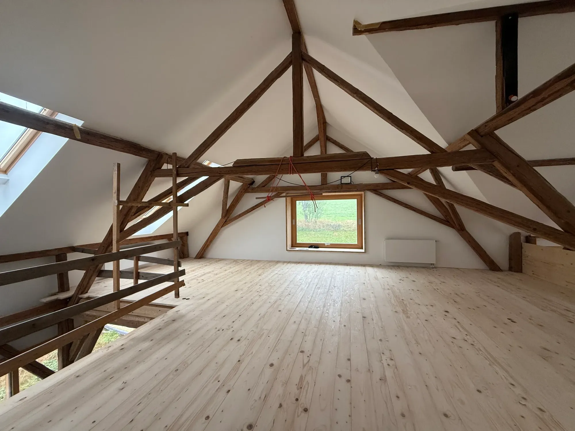 Blick über die Fichtendielen zum Giebelfenster und alten Dachtragwerk