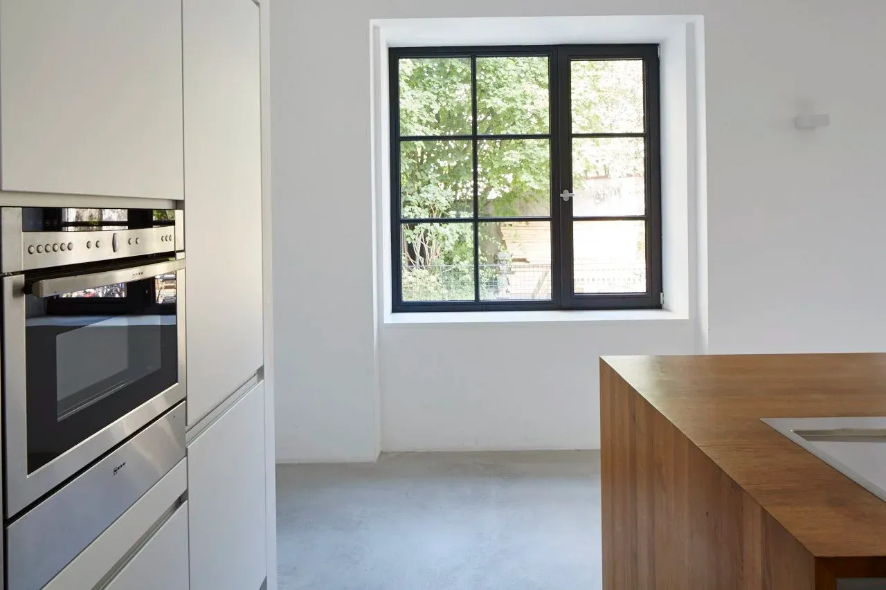 Küche mit Einbaubackofen und Sprossenfenster zum Garten