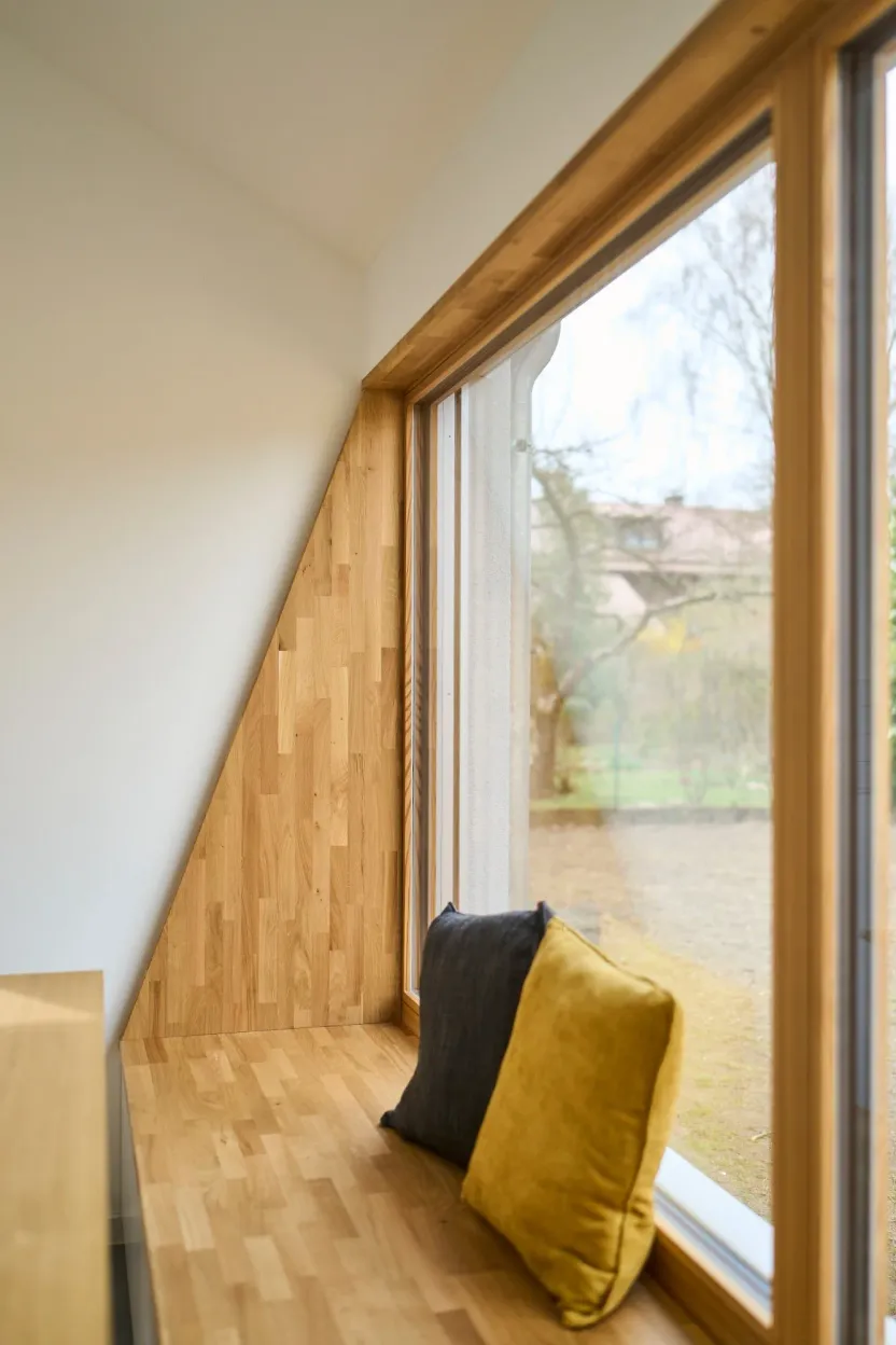 Sitzfenster mit Holzlaibung unter der Dachschräge, zwei Kissen, Blick in den Garten