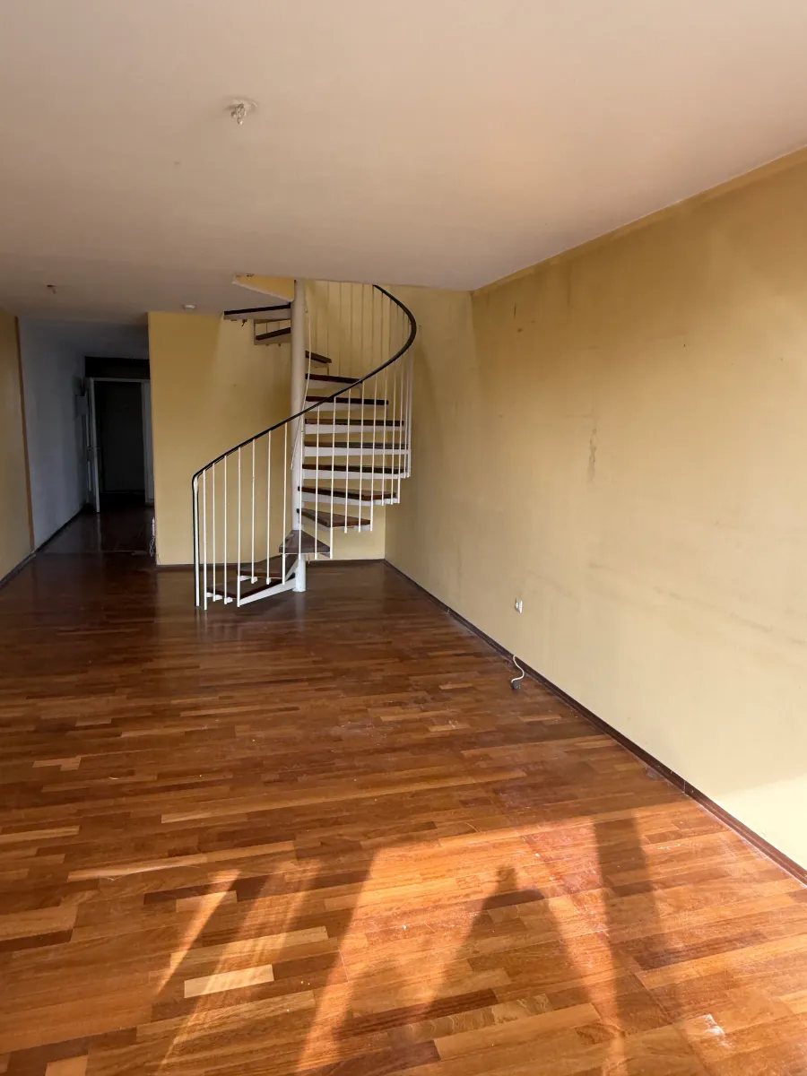 Wohnraum im Bestand mit gelben Wänden, Holzboden und Wendeltreppe