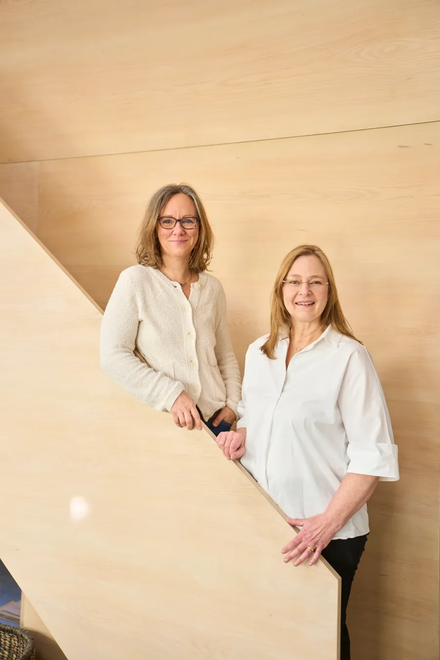 Eva Petri und Birte Raff, Gründerinnen von pur architekten, auf einer Holztreppe