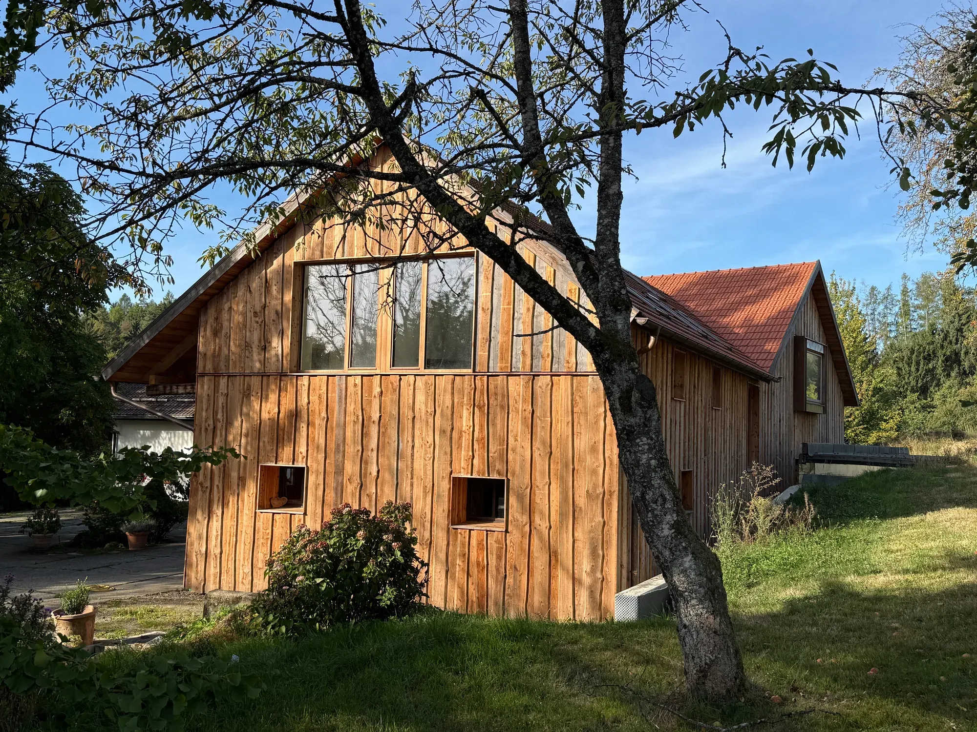 Umgebaute Scheune mit heller Holzfassade und großen Giebelfenstern