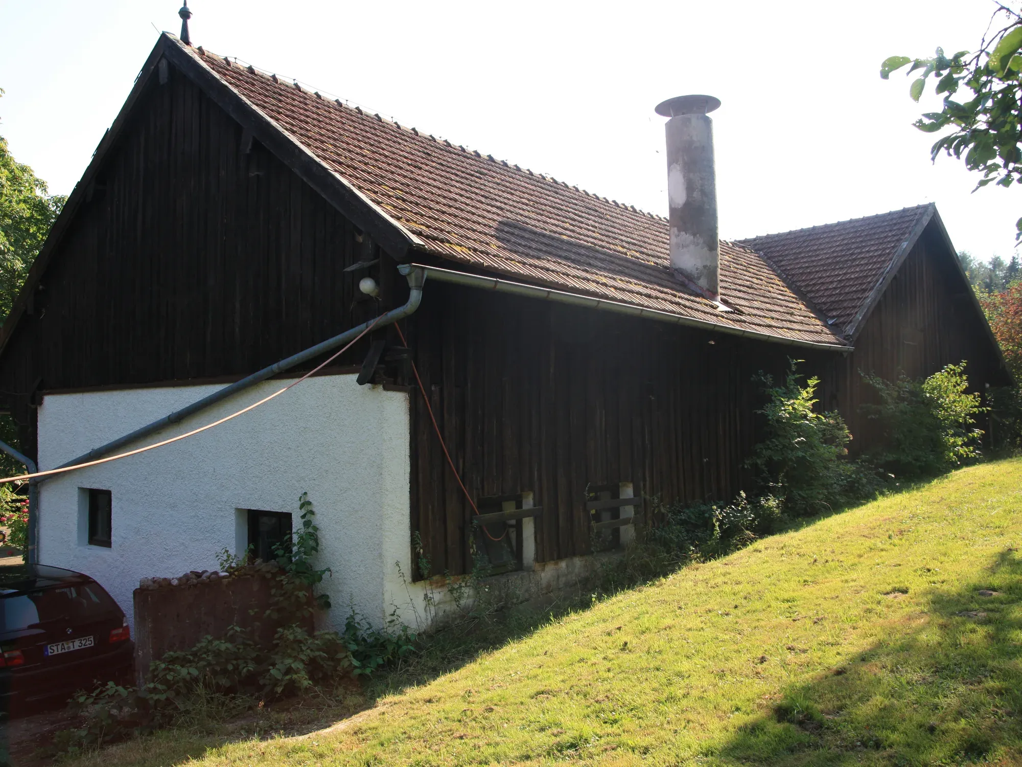 Scheune vor dem Umbau mit dunkler Holzfassade und Ziegeldach