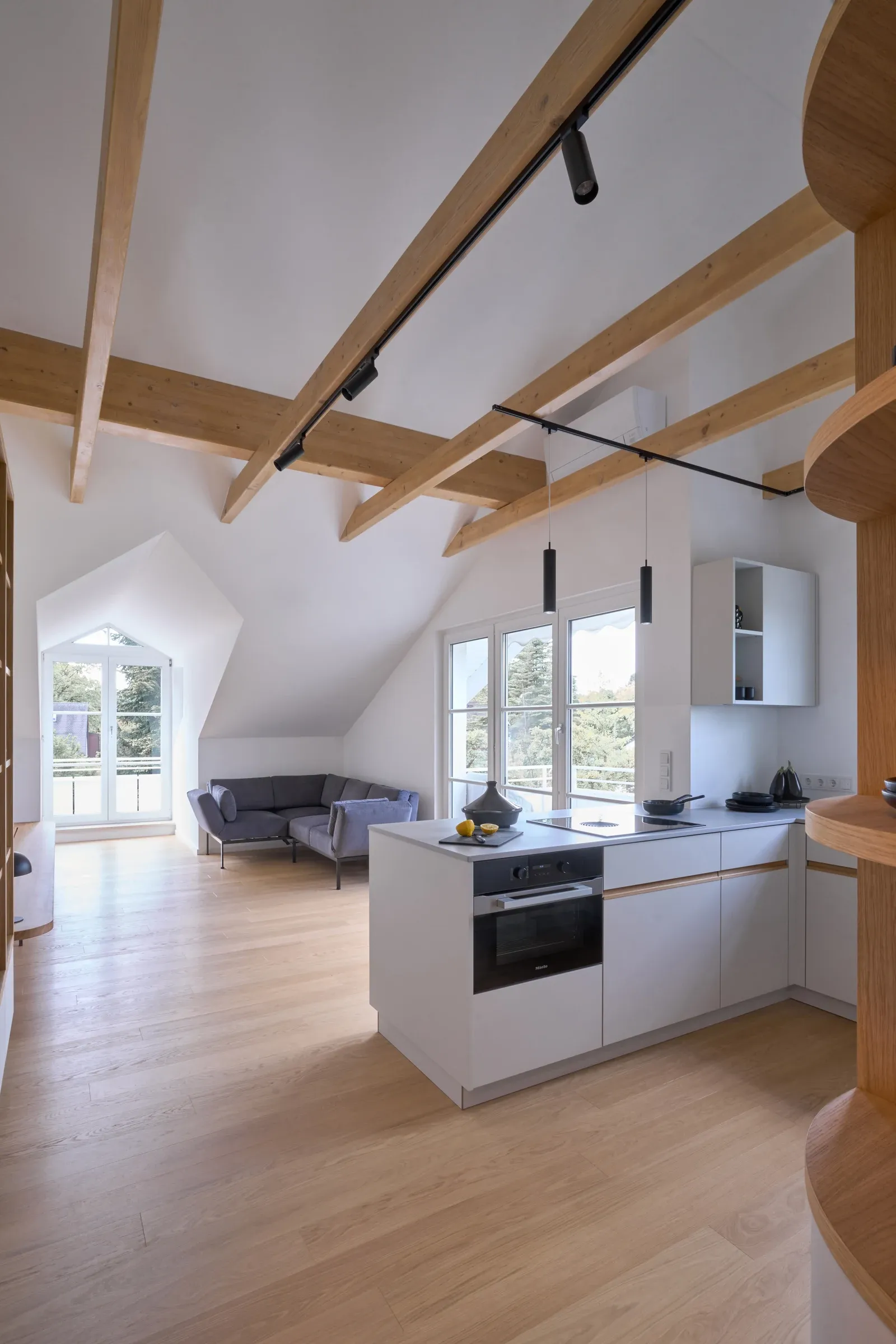 Wohnraum nach der Sanierung mit weißer Deckenverkleidung, sichtbaren Holzbalken, neuer Küche und Eichendielen
